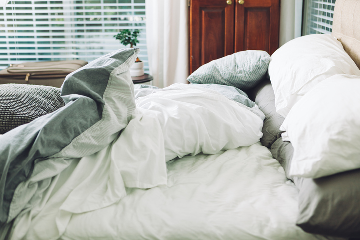 An adult bed with large puffy pillows and a big thick quilt on it.